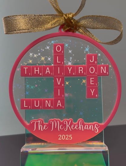 Personalized Christmas ornament with names and year, tied with a gold ribbon.